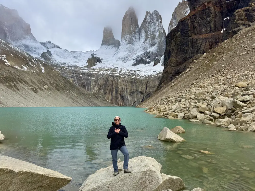 Caminante con las manos en el corazón frente a las Torres del Paine
